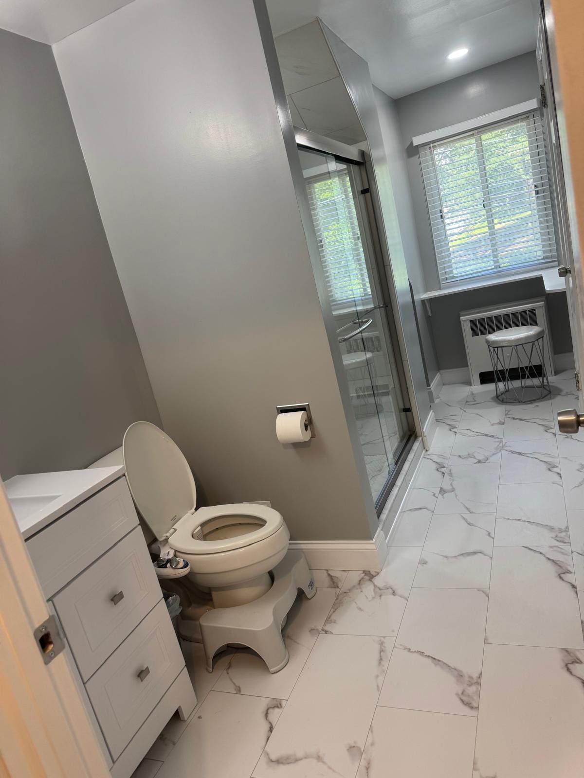Finished bathroom with marble-look tile and a glass shower